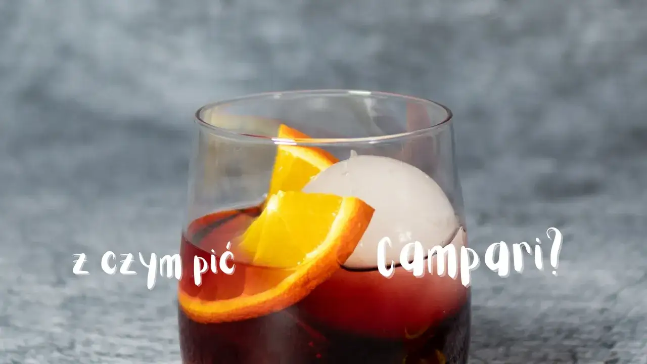 Z czym pić Campari? Szklanka z czerwonym drinkiem, lodem i plasterkami pomarańczy.