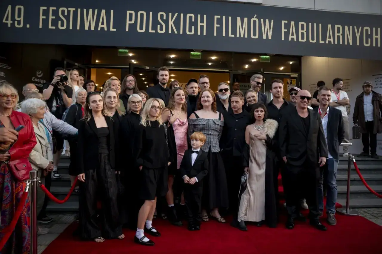Grupa polskich aktorów pozuje na czerwonym dywanie przed budynkiem festiwalowym.