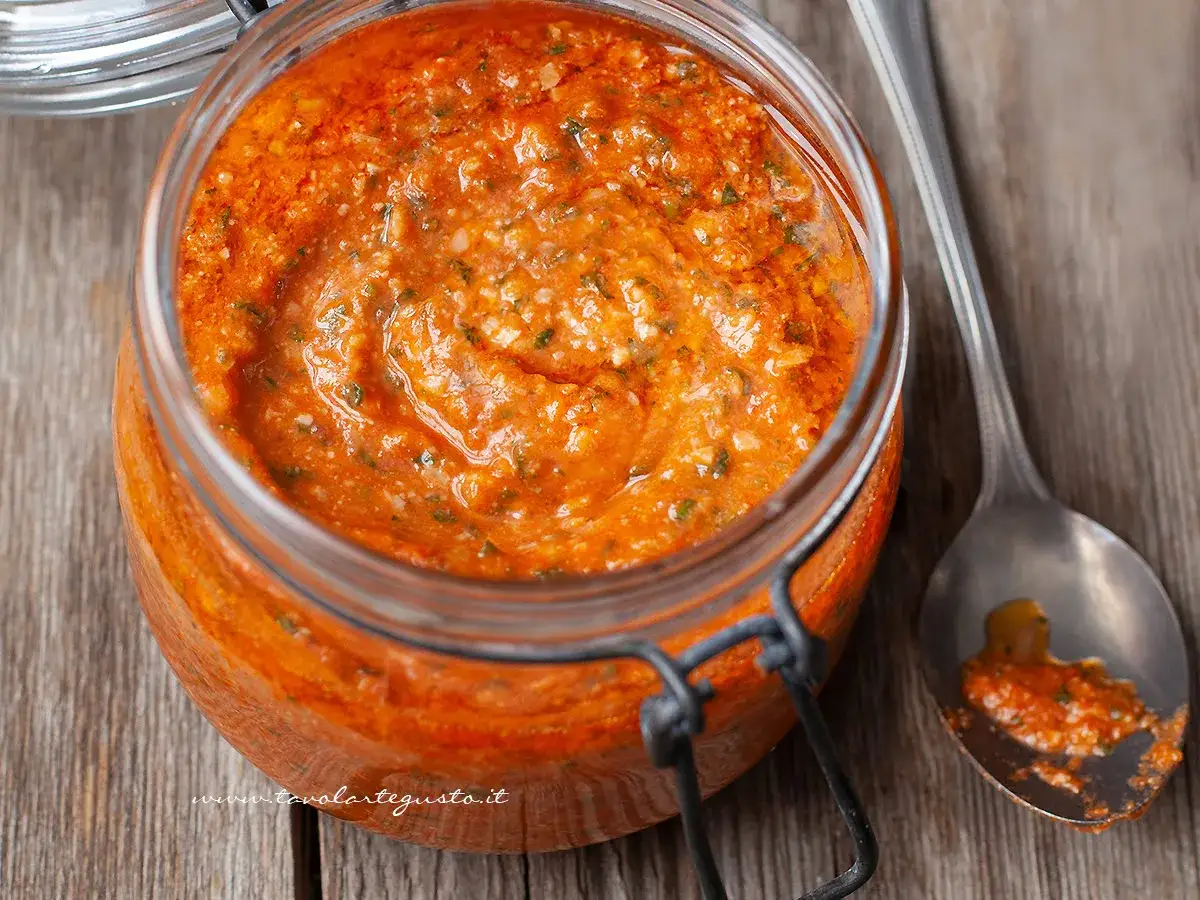 Vasetto di pesto alla trapanese, un condimento rosso vibrante con pomodori, mandorle e basilico, pronto per condire la pasta.