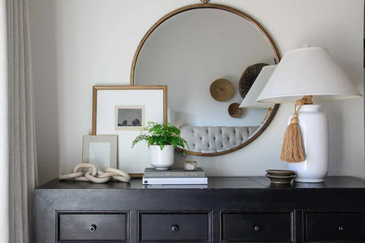 Ideas on how to decorate a dresser: a framed print, a plant, books, a lamp, and decorative chain create a stylish vignette.