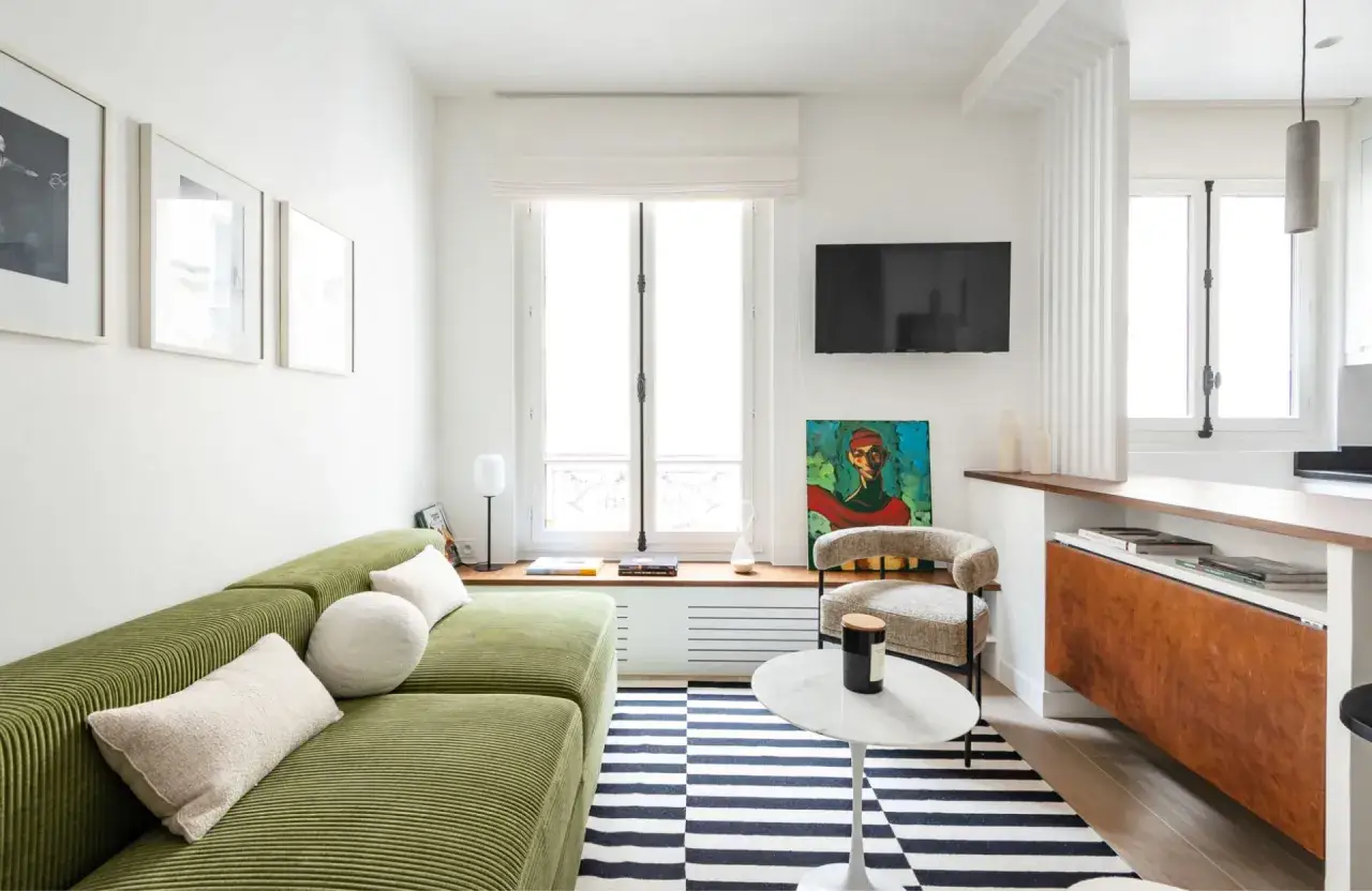 Un salon aux couleurs vives, avec un canap&eacute; vert c&ocirc;tel&eacute;, un tapis ray&eacute; et une peinture audacieuse, &eacute;voquant un style **salon ann&eacute;es 70**.