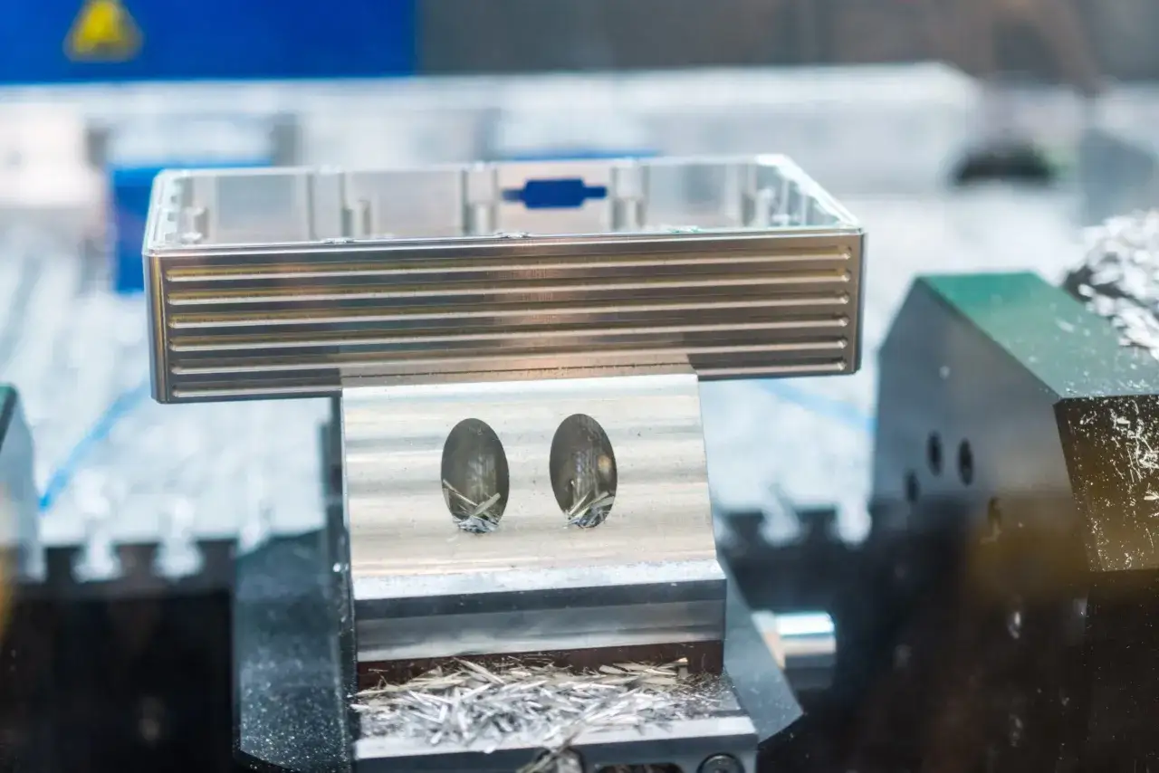 Precyzyjne frezowanie aluminium w procesie produkcyjnym. Widać obrabiany element i wióry.