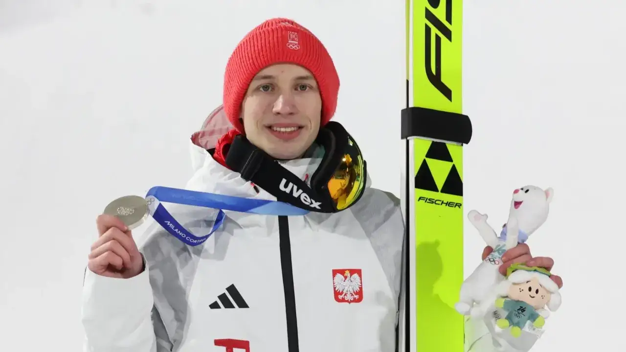 Kacper Tomasiak z medalem i maskotkami, obok nart.