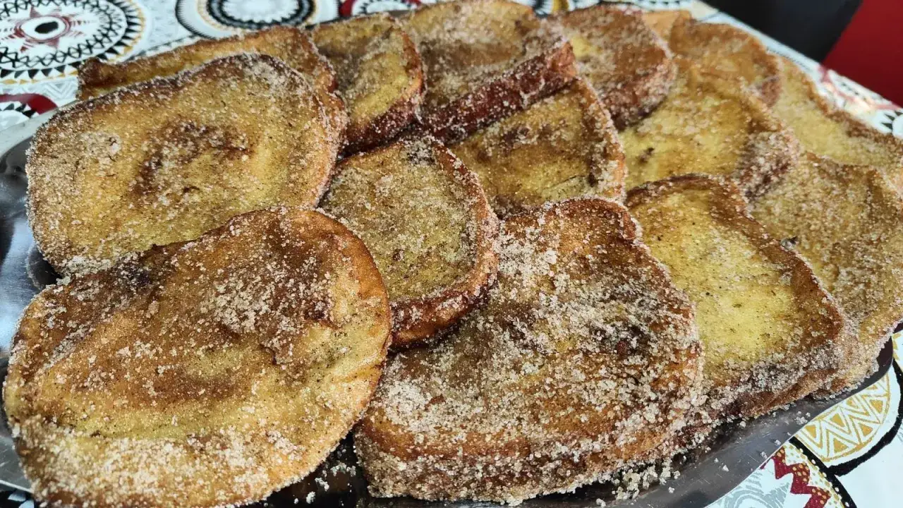 Un plato lleno de torrijas de leche, doradas y espolvoreadas con azúcar y canela, listas para disfrutar.