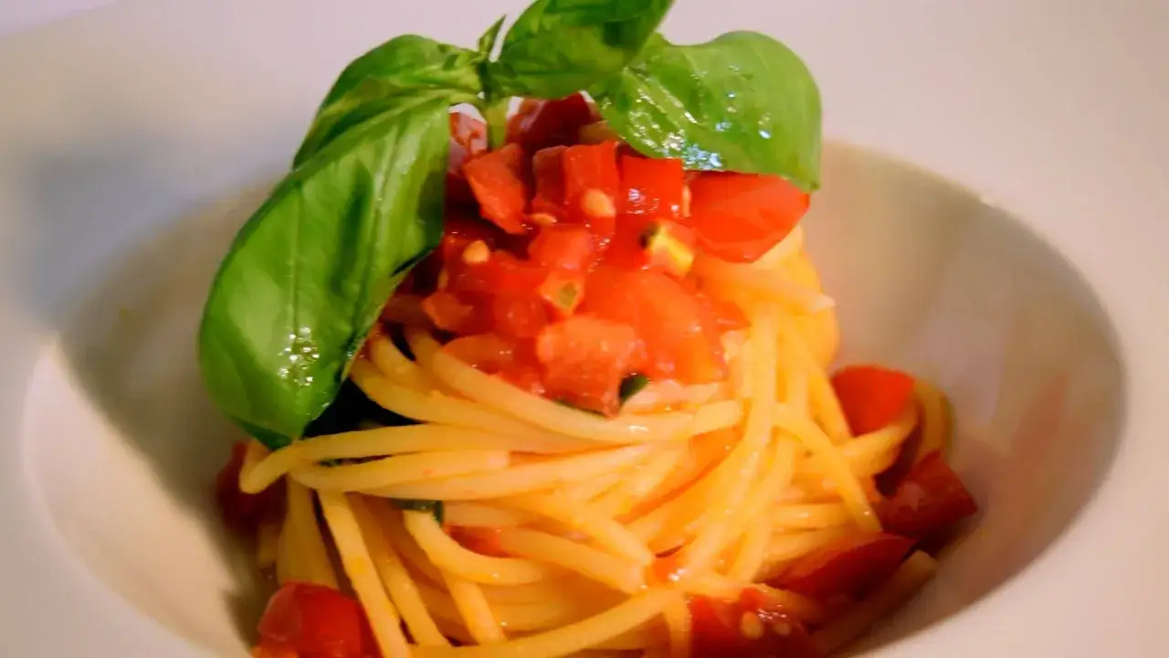 Spaghetti conditi con un fresco sugo con pomodorini freschi e basilico, un piatto semplice e gustoso.