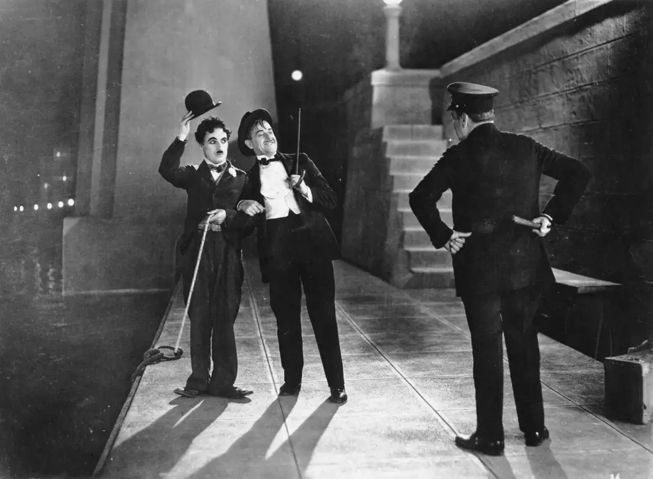 Charlie Chaplin och en vän i en klassisk scen från hans filmer, möter en polis.