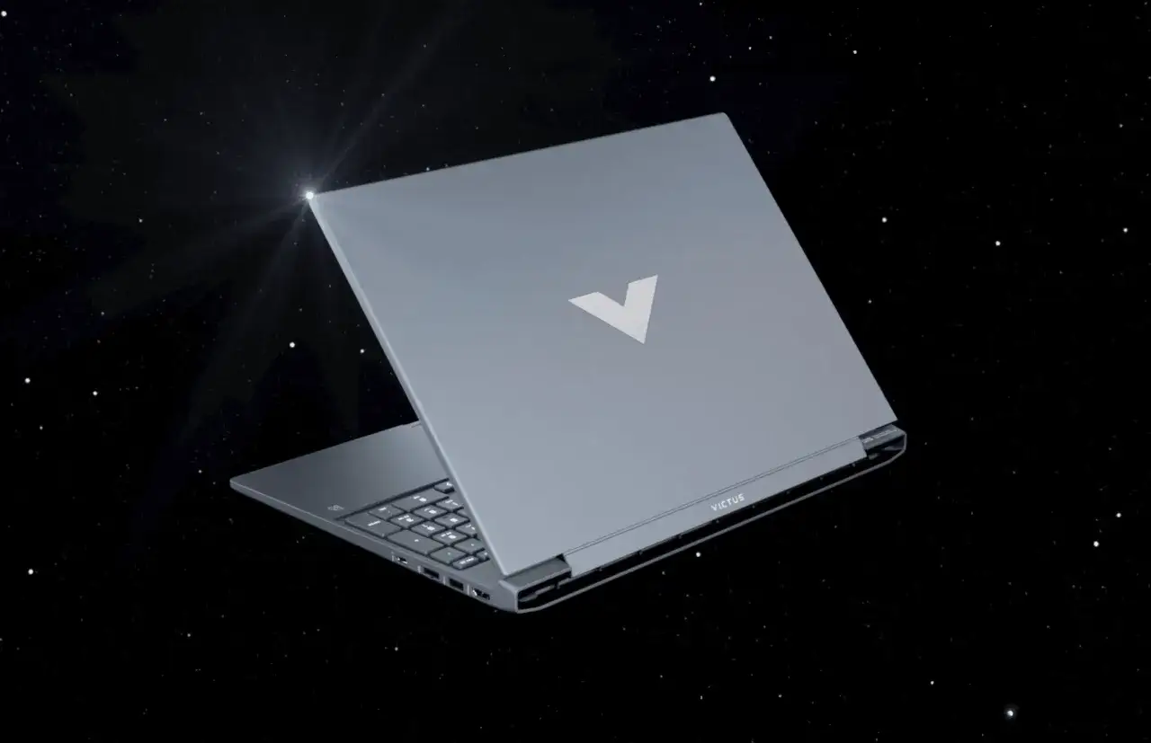 Szary laptop gamingowy Victus z podświetlanym logo V na tle kosmosu.