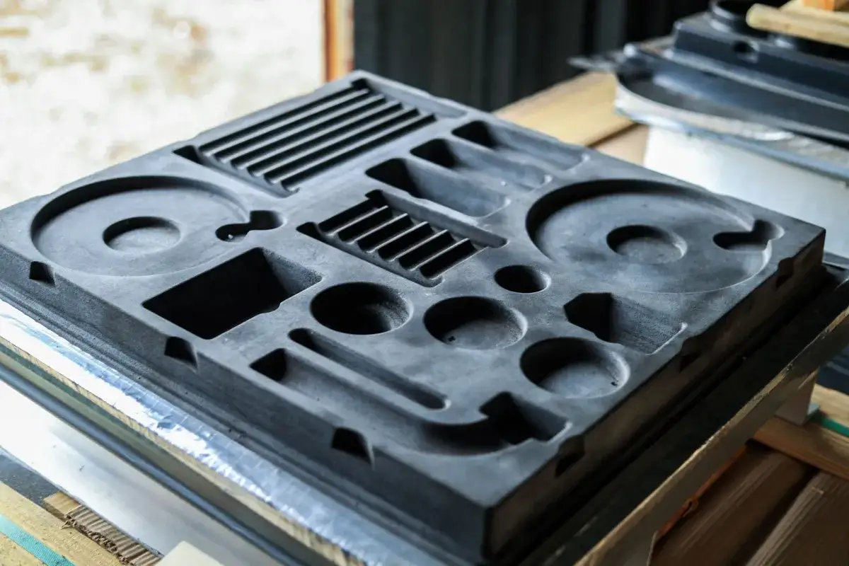 A dark gray, multi-compartment mold, possibly for packaging or manufacturing, showcasing the intricate details of how to make acrylic molds.