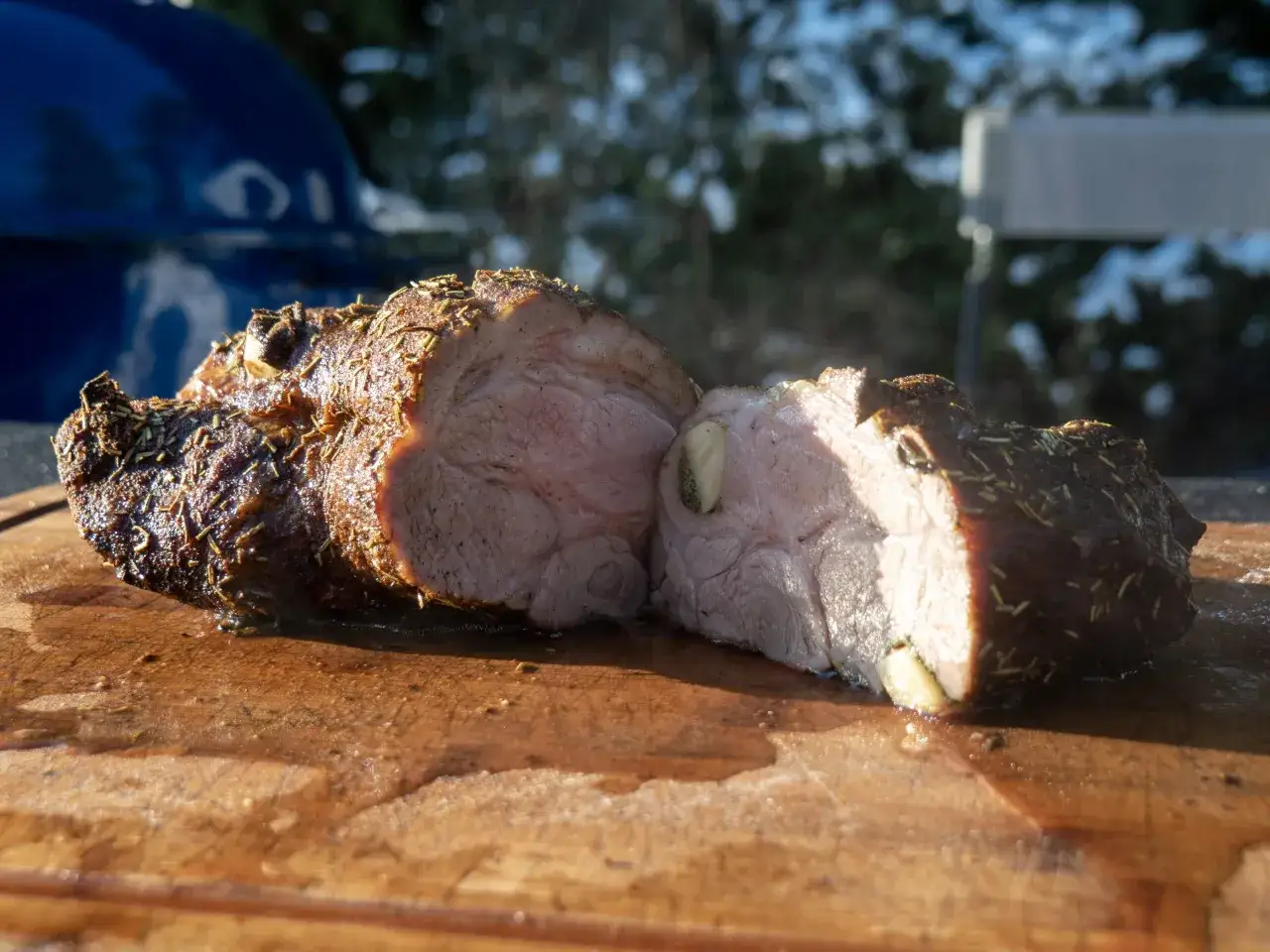 Soczysta karkówka na grillu elektrycznym, przyprawiona ziołami, leży na drewnianej desce.
