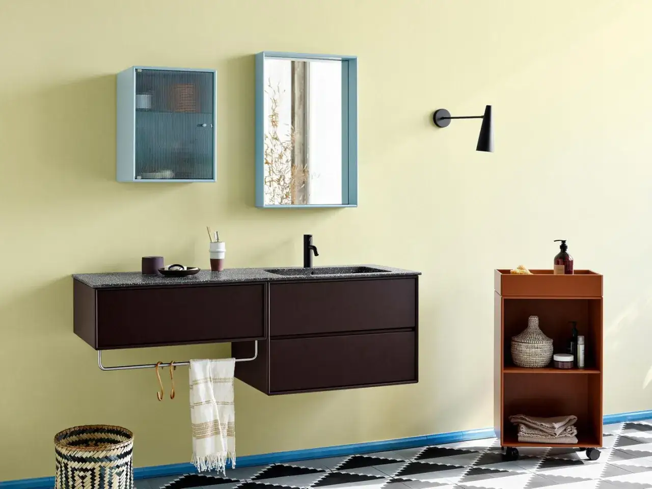 Moderne Farbgestaltung kleines Badezimmer: Gelbe Wände, dunkles Waschtischmöbel, hellblaue Spiegelschrank und ein orangefarbener Rollwagen.