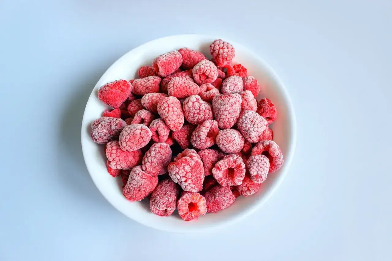 En vit sk&aring;l fylld med frysta hallon. Dessa hallon nyttigt &auml;r perfekta f&ouml;r smoothies eller bakning.