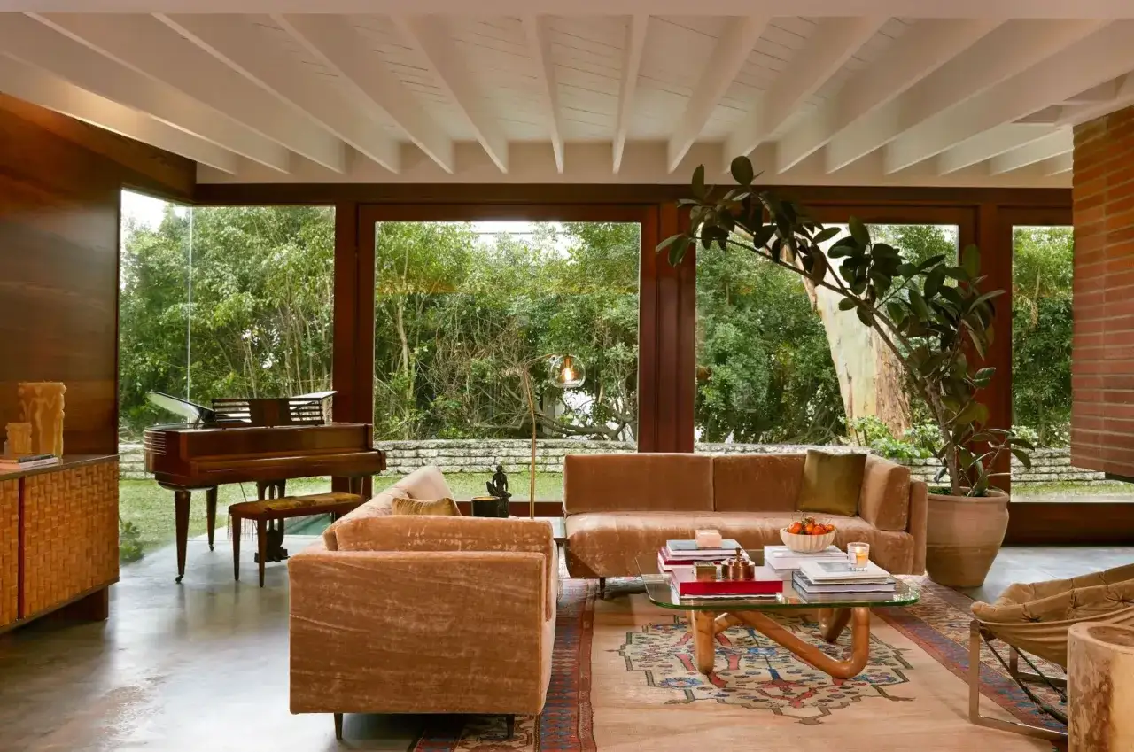 Gem&uuml;tliches Wohnzimmer im Midcentury Modern Stil mit Samtsofas, Klavier und gro&szlig;em Fenster zur Natur.