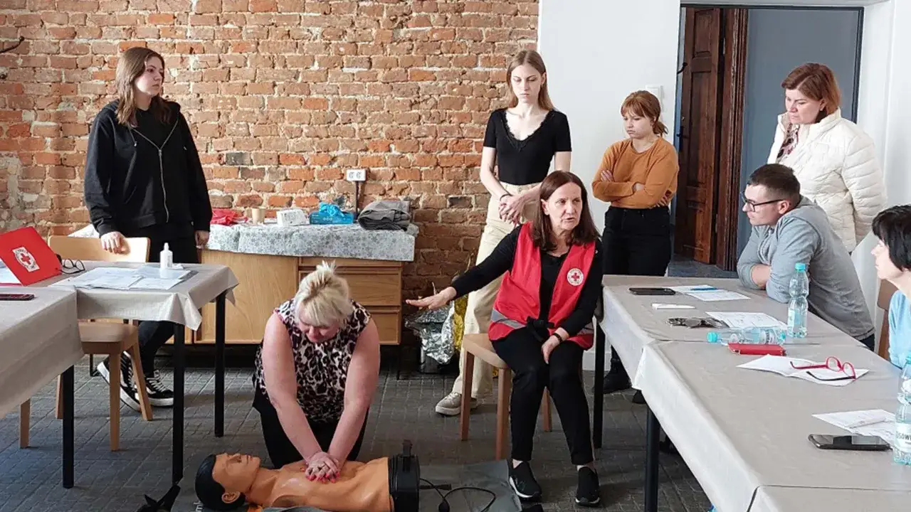 Grupa osób ćwiczy resuscytację na fantomie. To praktyczna część kursu KPP. Cena takiego szkolenia jest przystępna.