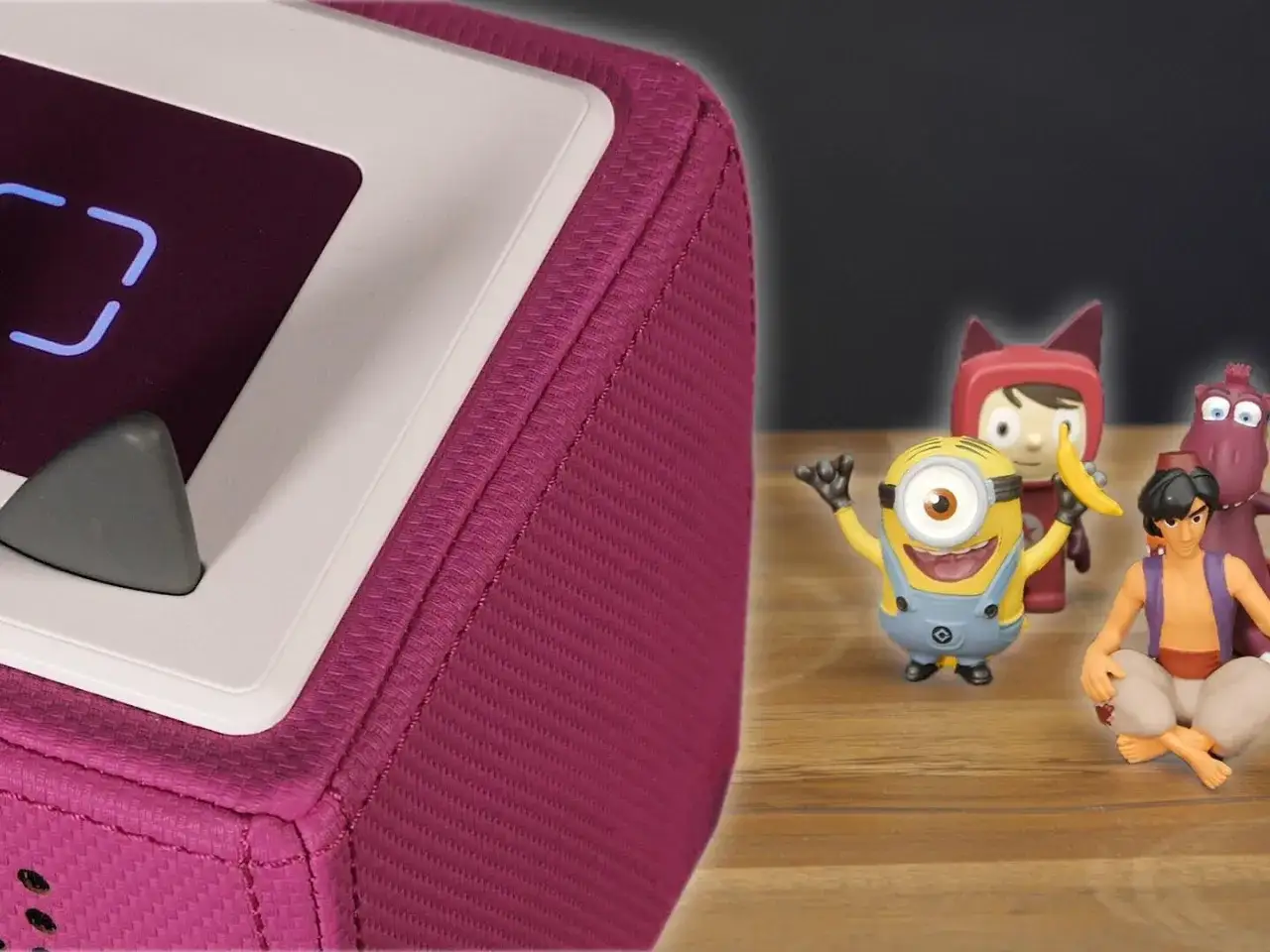 Die pinke Toniebox blinkt blau. Ein Minion, Aladdin und andere Figuren warten gespannt auf die Geschichte.