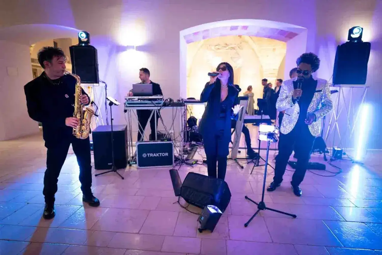 Una band suona musica per un matrimonio, con un sassofonista, una cantante e un cantante con giacca scintillante.