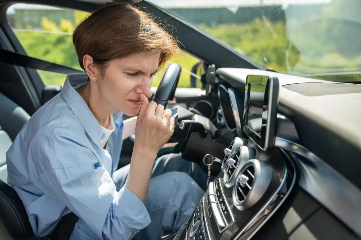 Kobieta w samochodzie zatyka nos, czując nieprzyjemny zapach spalin w samochodzie diesel.