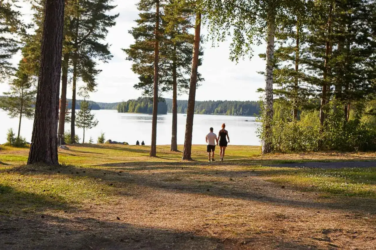 Ett par promenerar hand i hand vid en sjö, en idyllisk plats för första camp ansia.