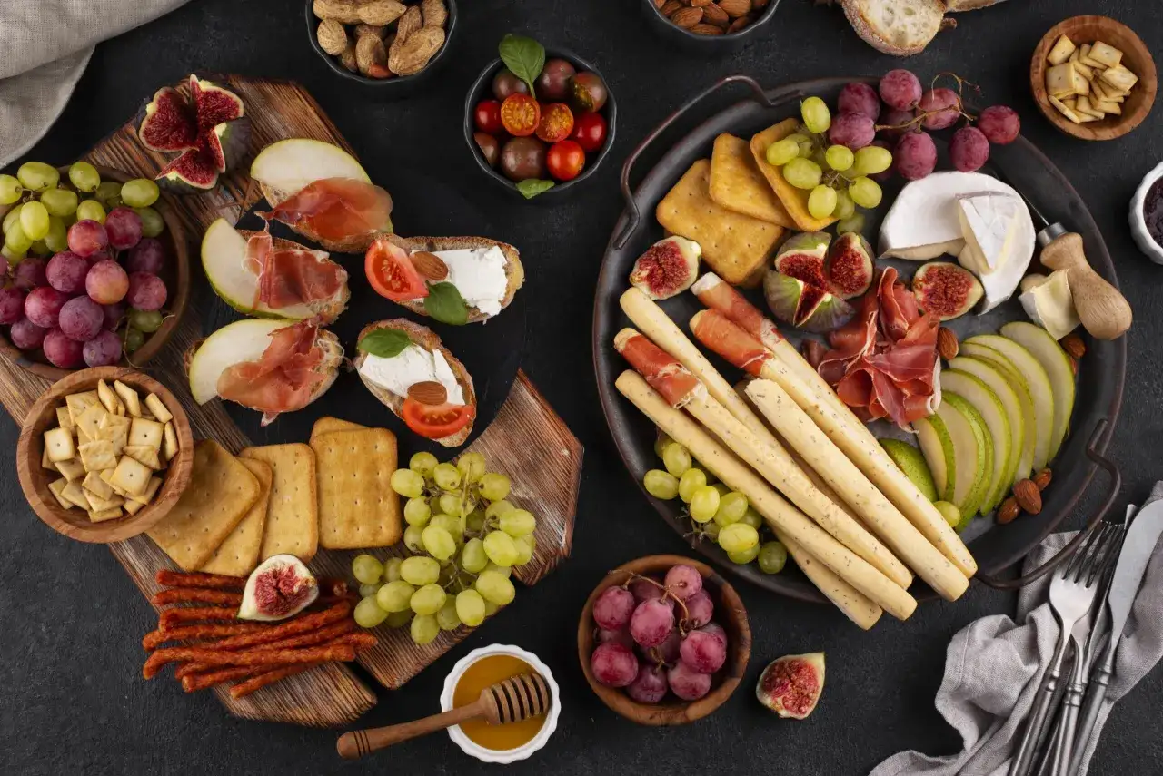 Pyszne włoskie przekąski: deska serów, prosciutto, figi, winogrona, grissini i krakersy.