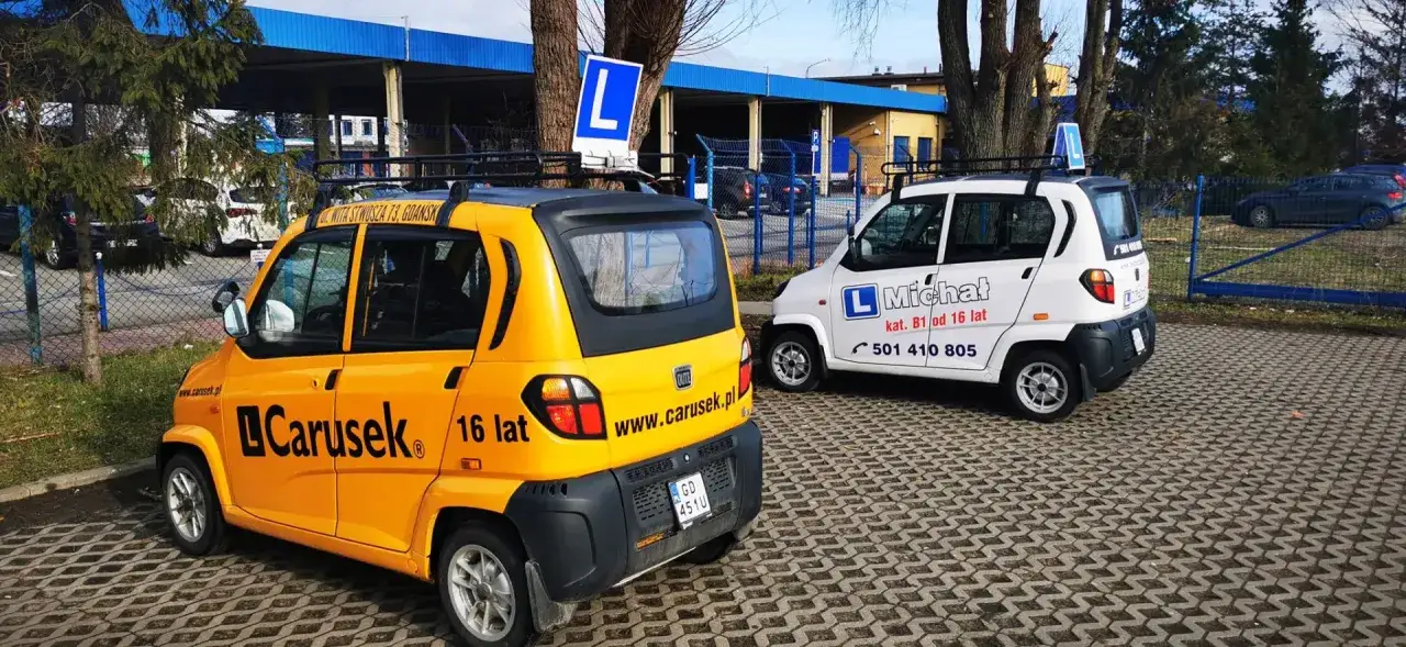 Dwa samochody szkoleniowe, żółty i biały, z oznaczeniem