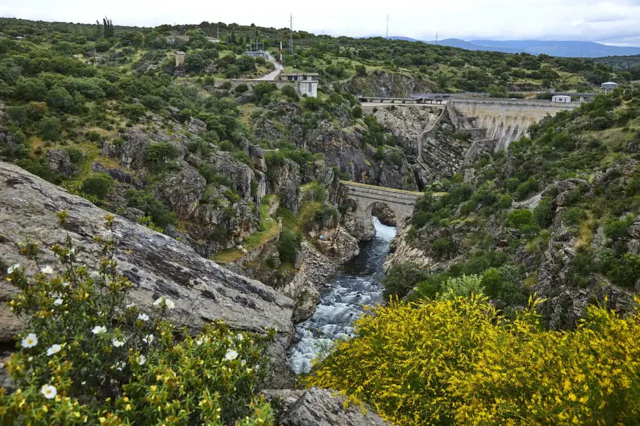 Paisaje natural con un r&iacute;o caudaloso, un puente de piedra y una presa. Ideal para saber **que ver en Robledillo de la Jara**.