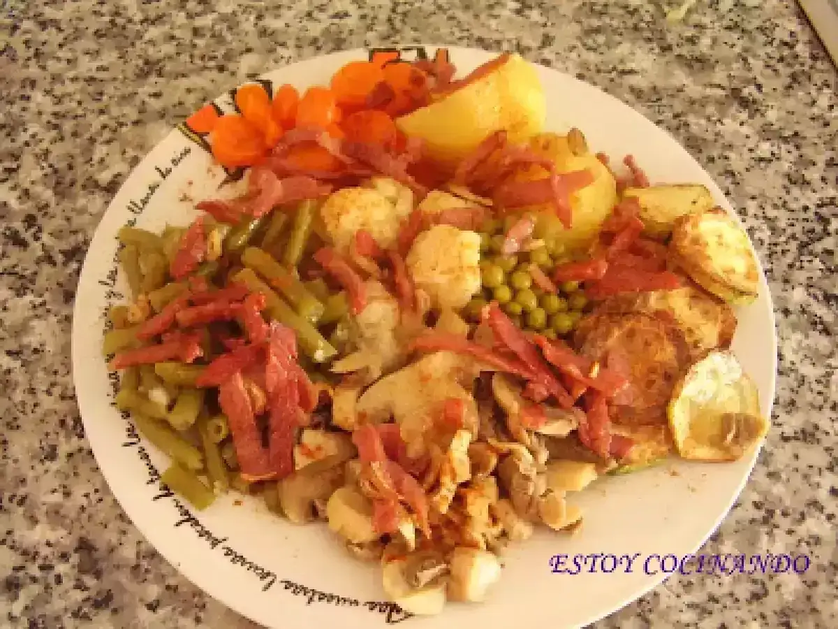 Un plato con un panache de verduras: jud&iacute;as verdes, guisantes, zanahorias, patatas y champi&ntilde;ones, todo ello salpicado con trocitos de jam&oacute;n.
