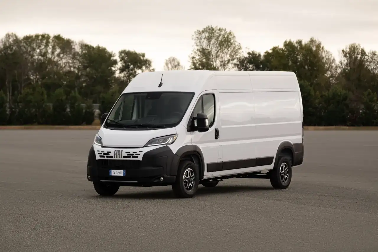 Biały Fiat Ducato 2.3 Multijet na pustym placu, z drzewami w tle. Może to być symbol problemu z brakiem mocy w tym modelu.
