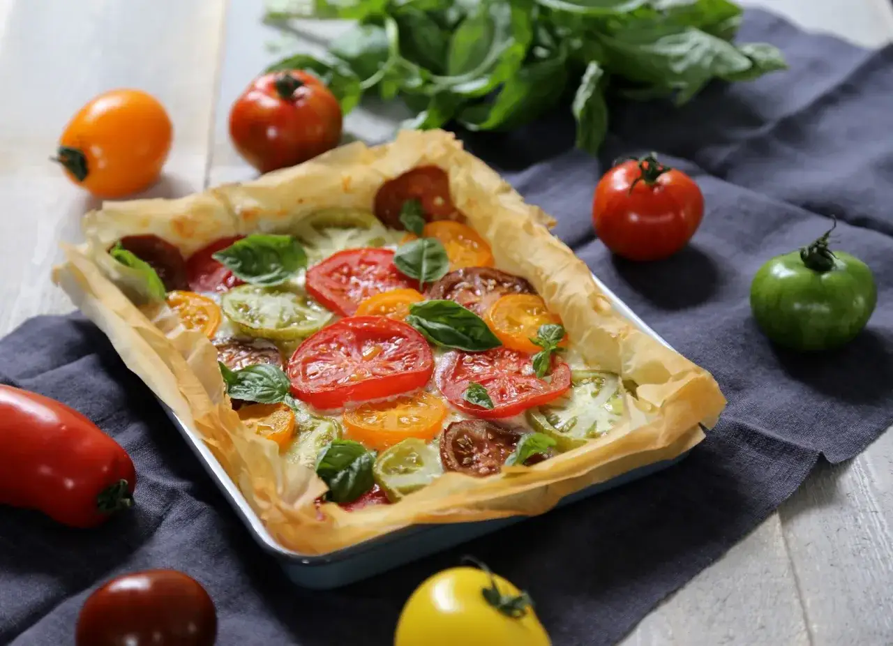 Tarte tomate ch&egrave;vre aux couleurs vives, garnie de tomates vari&eacute;es et de feuilles de basilic frais. Un d&eacute;lice visuel et gustatif.