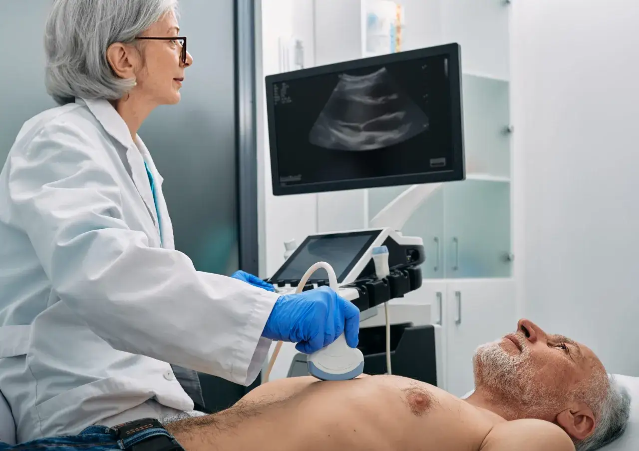 Läkare utför endoskopiskt ultraljud på en patient. Bilden visar en läkare med blå handskar som håller en ultraljudsgivare mot patientens mage, medan en ultraljudsbild visas på en skärm.