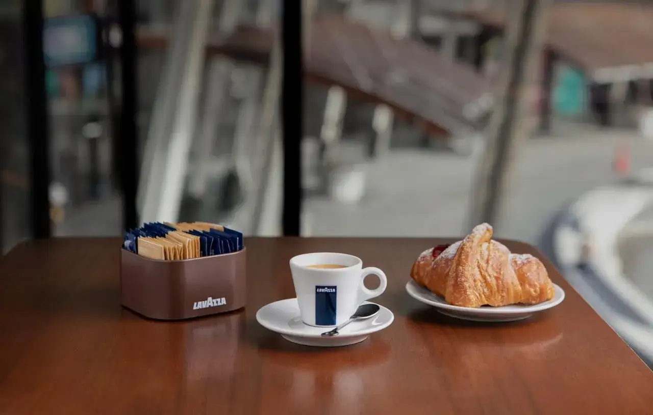 Un'autentica colazione italiana a casa: caffè Lavazza, croissant e zuccherini pronti per iniziare la giornata.