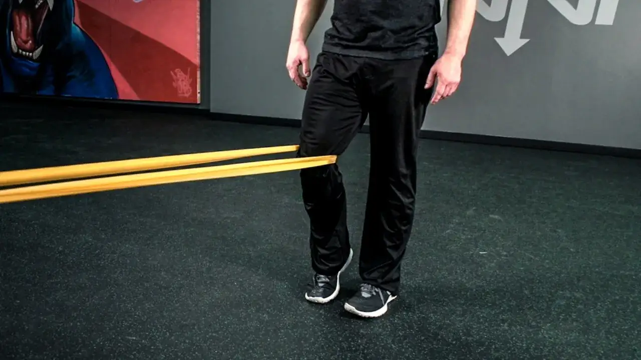 Mann trainiert mit Theraband am Knie.