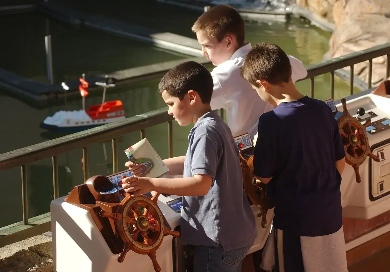 Ni&ntilde;os interact&uacute;an con maquetas de barcos y timones, una experiencia educativa que recuerda a los museos en Sevilla.