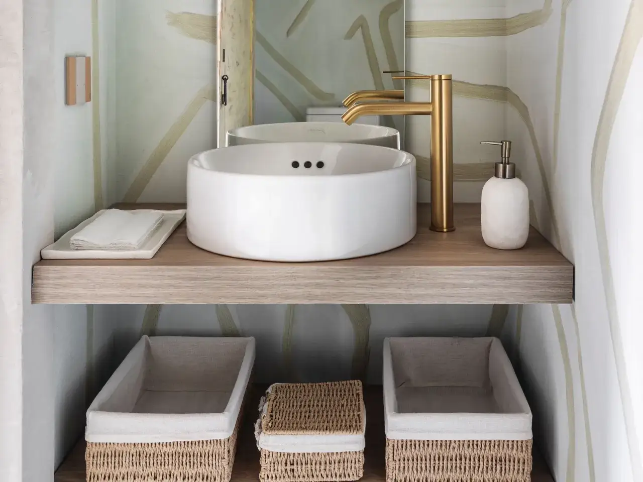 Cestas de mimbre y tela ofrecen pr&aacute;cticas ideas para debajo del lavabo, organizando el espacio con estilo.