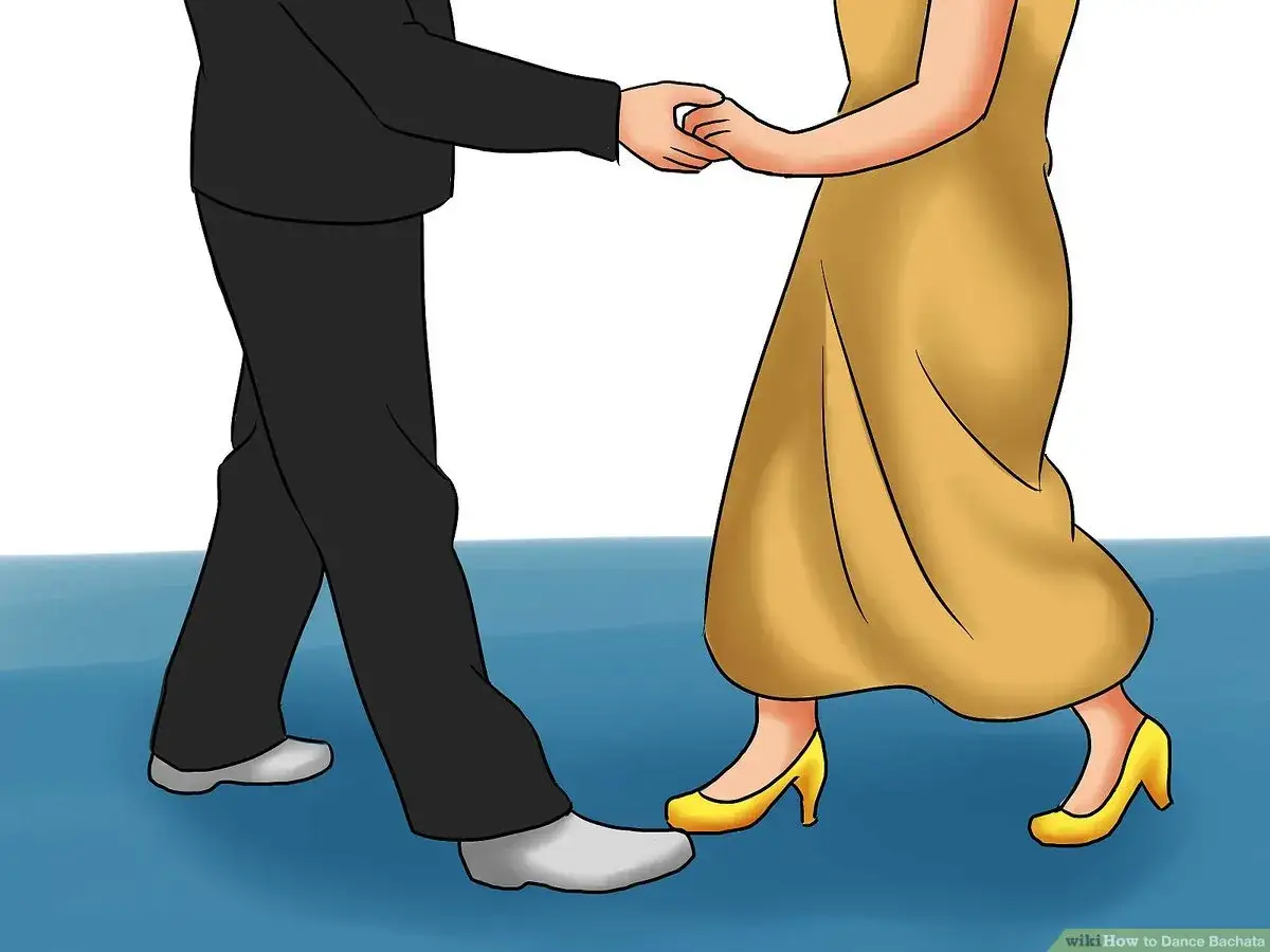Coppia che inizia a ballare bachata, lui in abito scuro, lei con un vestito giallo svolazzante.