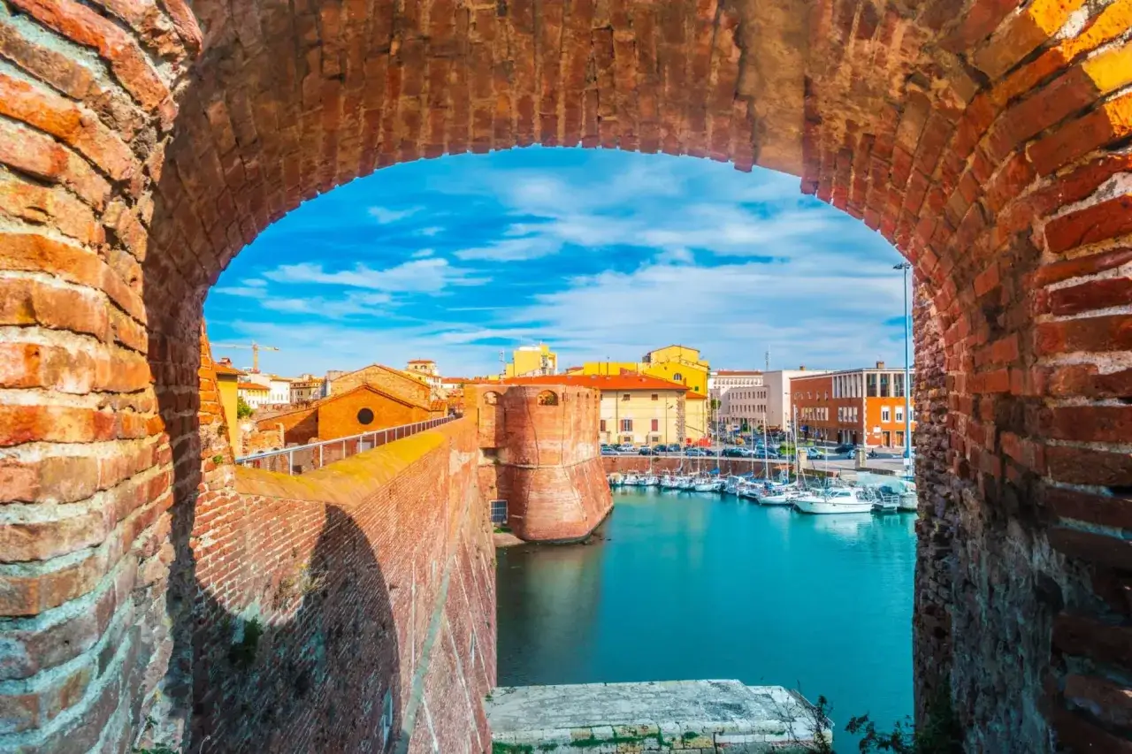 Widok na port w Livorno przez ceglany łuk. Warto zobaczyć fortyfikacje i zacumowane łodzie.