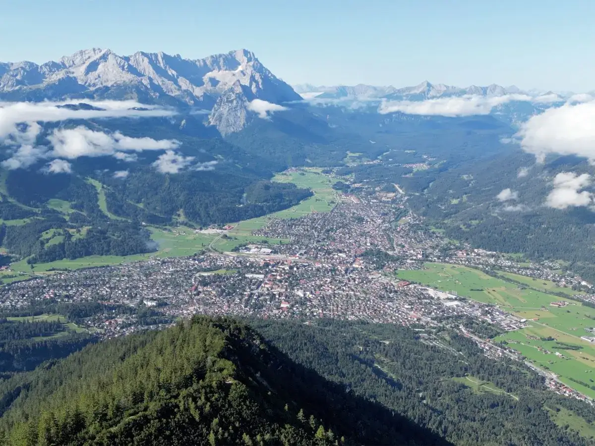 Blick über eine Stadt in einem Tal, umgeben von majestätischen berge in bayern. Wolken ziehen über die Gipfel.