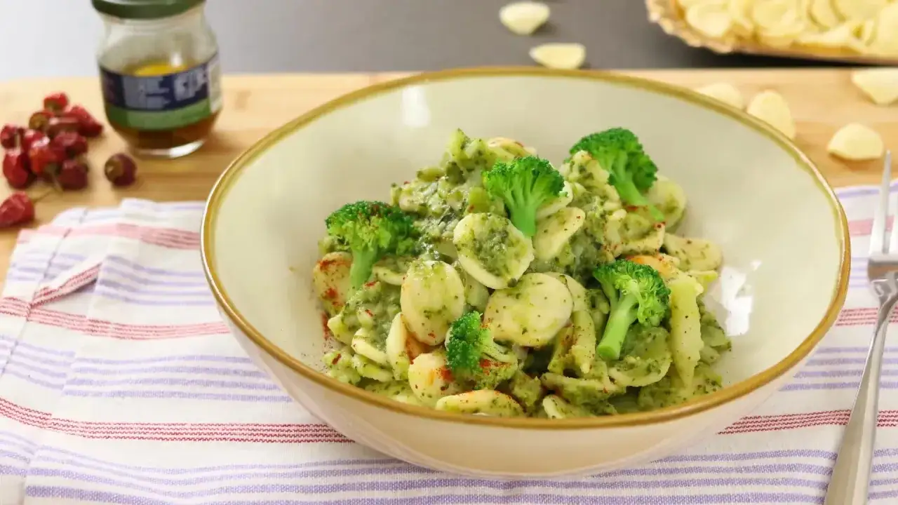 Un plato de pasta con br&oacute;coli, cubierto con una salsa verde cremosa y espolvoreado con piment&oacute;n.