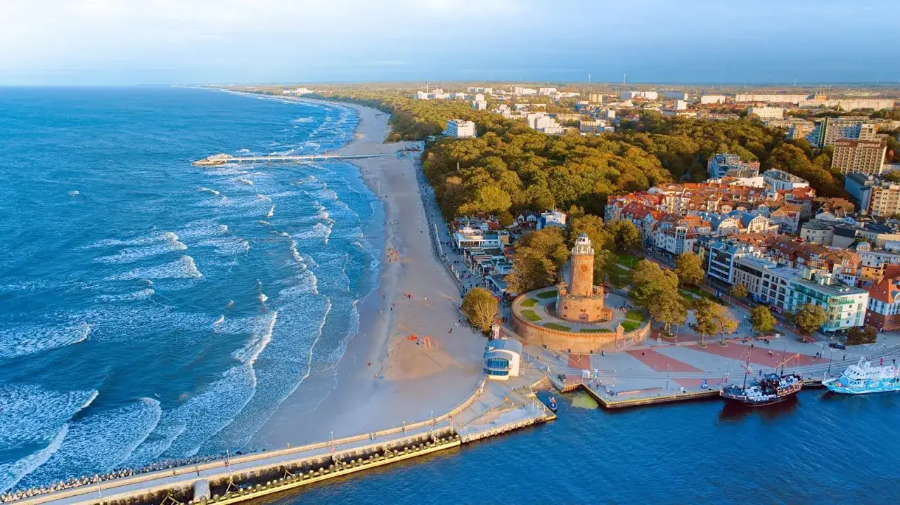 Widok na plażę, molo i latarnię morską w Kołobrzegu. Wspaniałe kołobrzeg atrakcje zachęcają do spacerów i podziwiania morza.