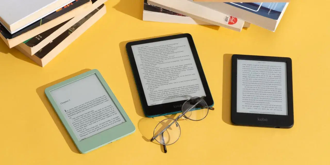 Zielony i czarny czytnik e-book&oacute;w obok stosu książek. Na ekranie czytnika widać tekst, jakbyś czytał mobi reader.