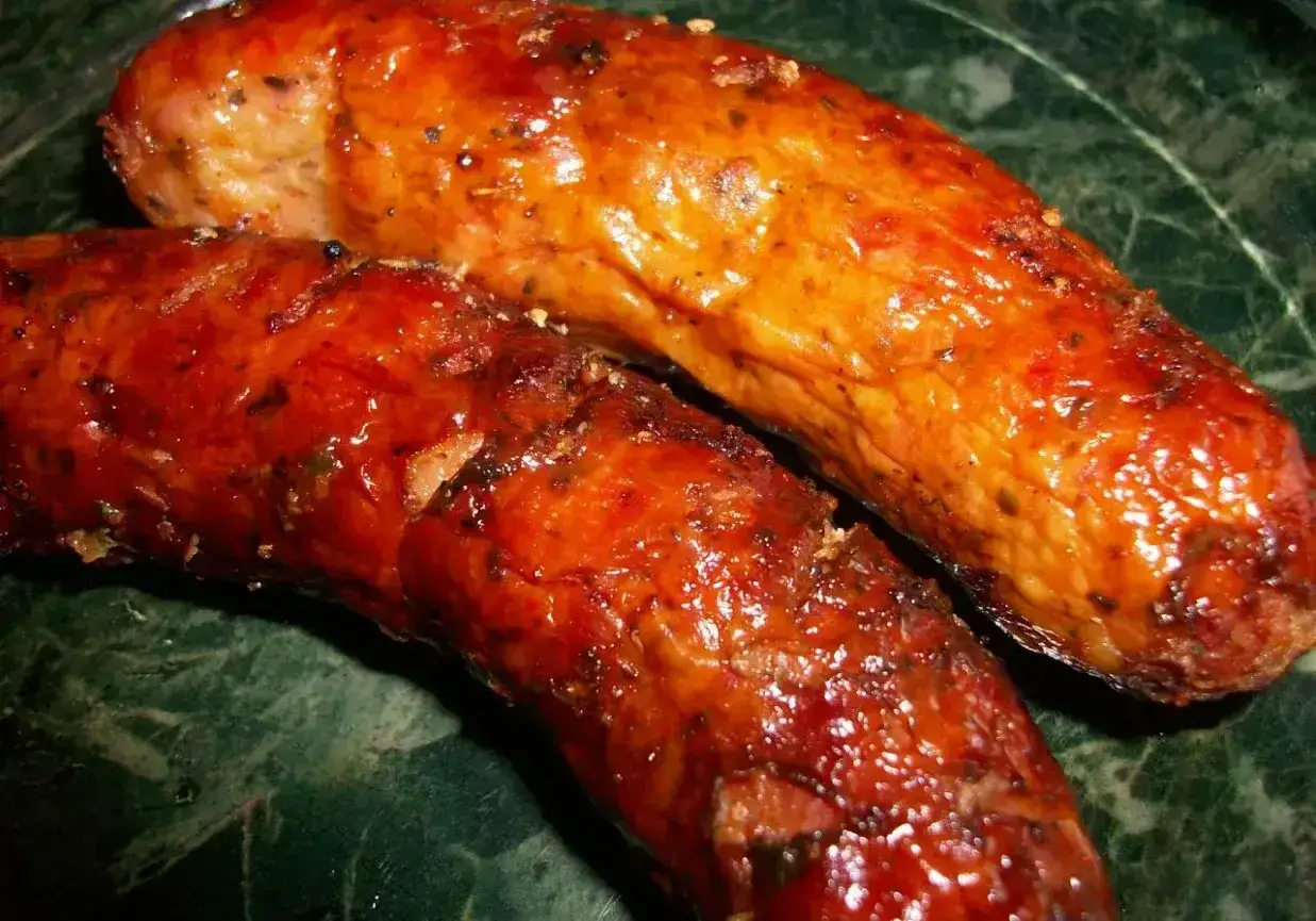 Dwie soczyste kiełbaski, idealnie zarumienione po grillowaniu w piekarniku. Odpowiednia temperatura to klucz do ich pysznego smaku.
