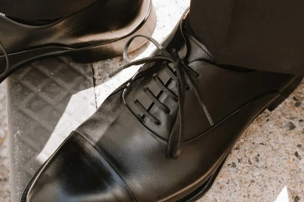 Schwarze Anzugschuhe mit gebundenen Schnürsenkeln, bereit für einen eleganten Auftritt.