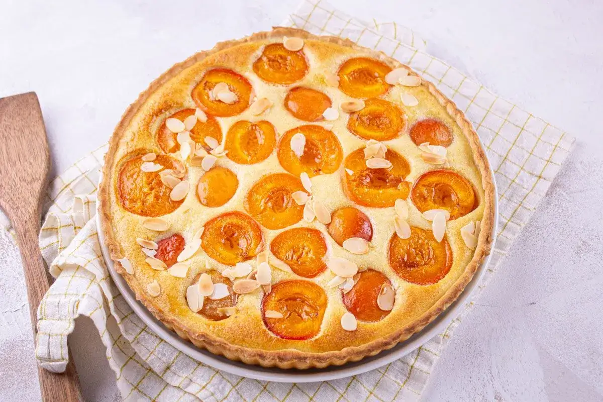 Tarte aux abricots dor&eacute;e, garnie de fruits juteux et d'amandes effil&eacute;es, pr&ecirc;te &agrave; &ecirc;tre d&eacute;gust&eacute;e.