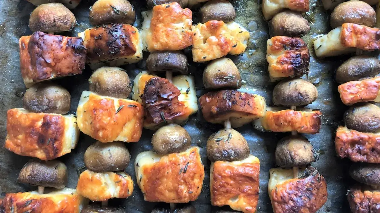 Gegrillte Champignons und Käse-Spieße, goldbraun und mit Kräutern bestreut, bereit zum Genießen.
