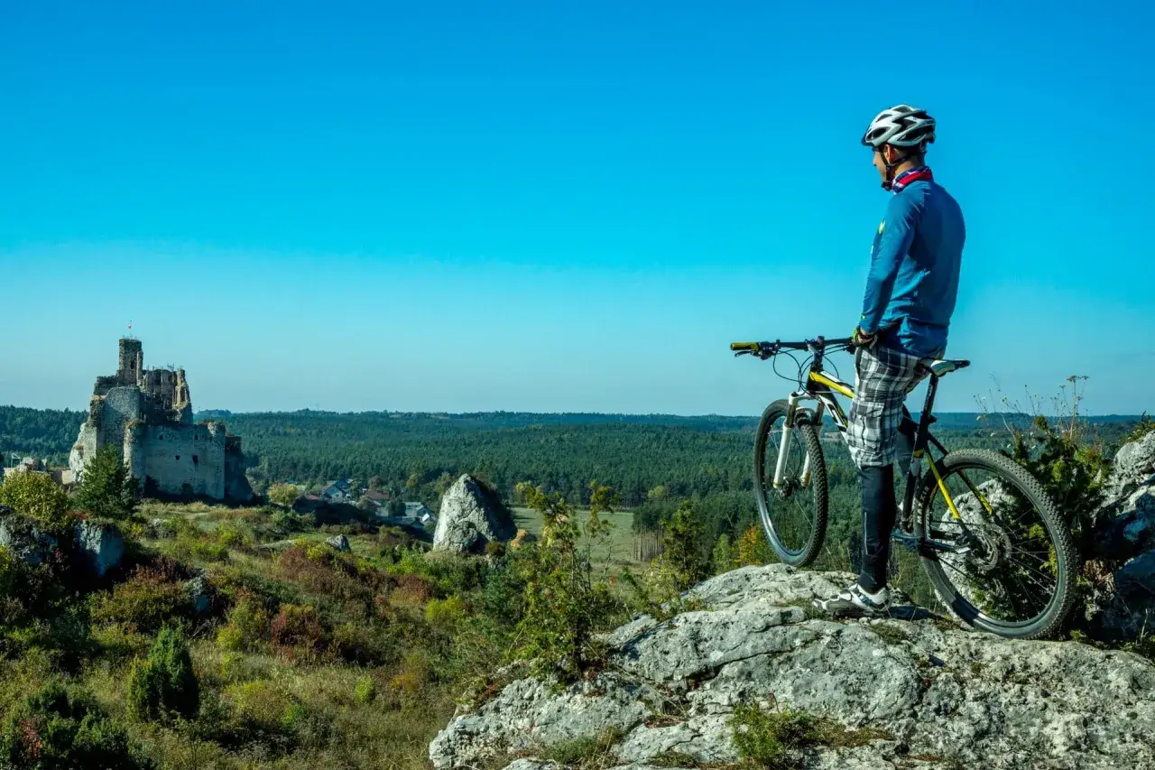 Rowerzysta na skale podziwia ruiny zamku i malownicze trasy rowerowe Częstochowa.