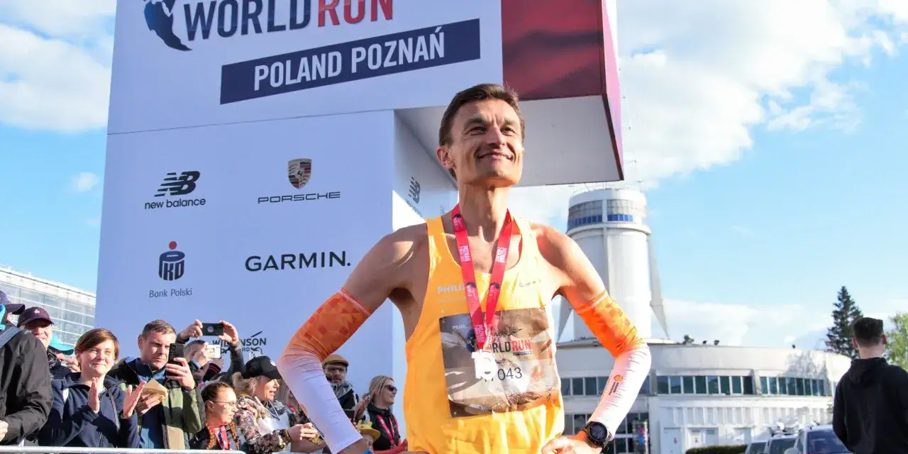Uśmiechnięty Dariusz Nożyński po biegu World Run Poznań, z medalem na szyi i numerem startowym 043.