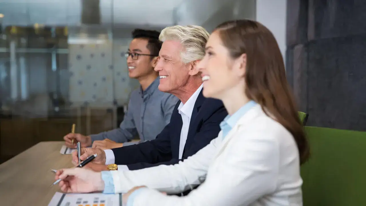 Diverse professionals in a meeting, discussing leadership vs management.