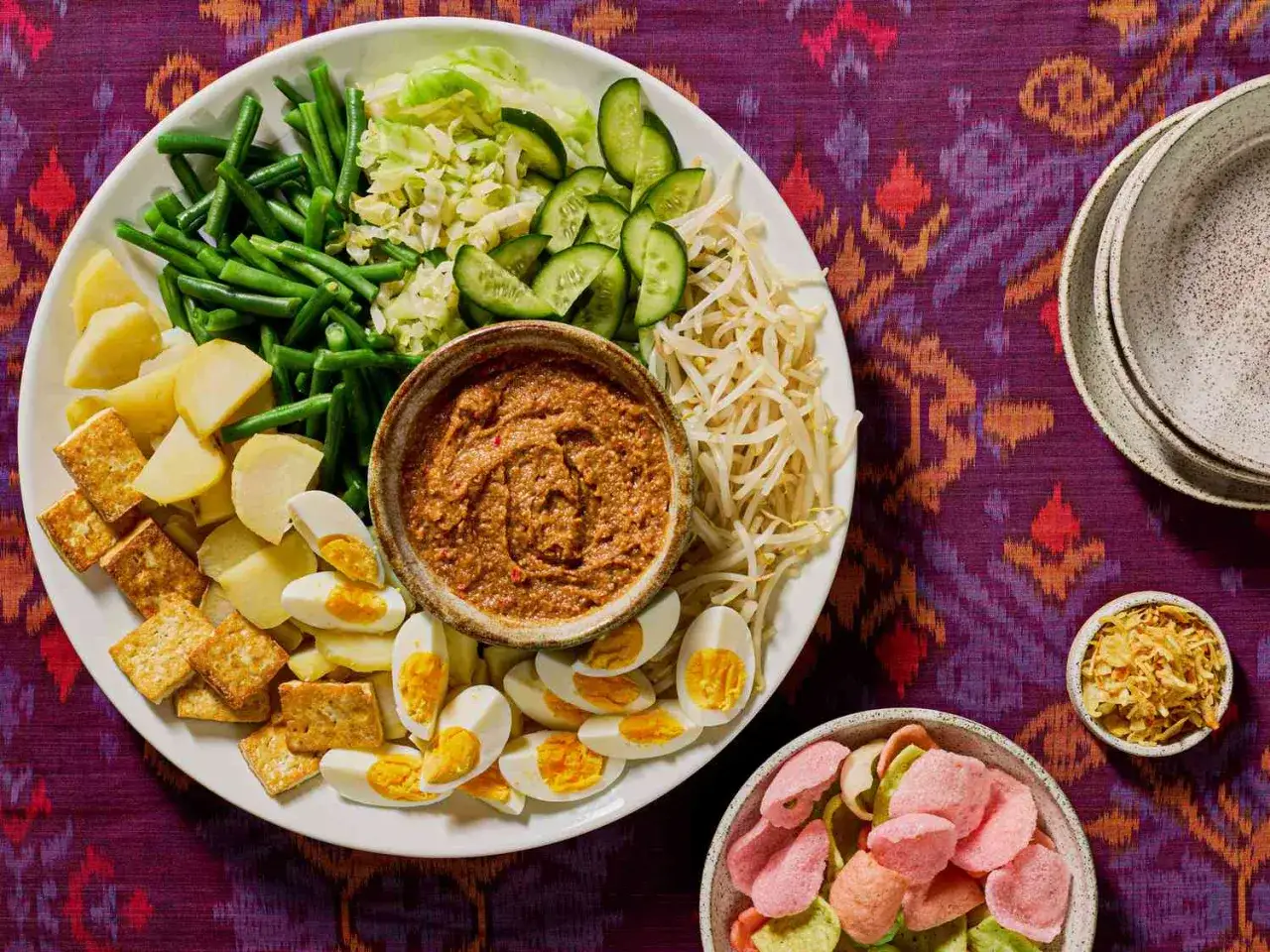 En stor tallrik med gado gado: kokt potatis, gröna bönor, kål, gurka, böngroddar, ägg, tofu och jordnötssås.