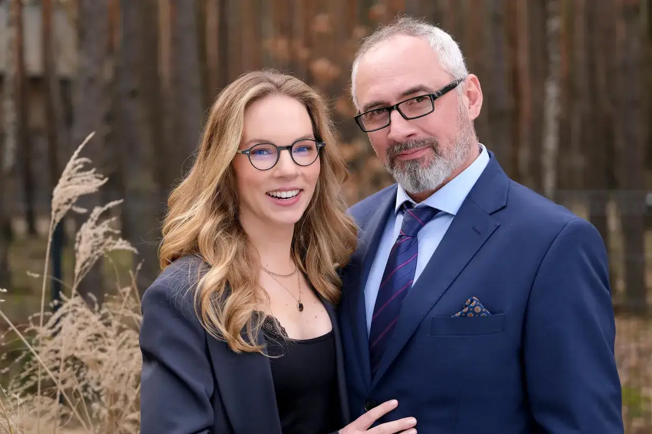 Hanna Turnau z mężem, uśmiechnięci, w okularach, na tle przyrody.