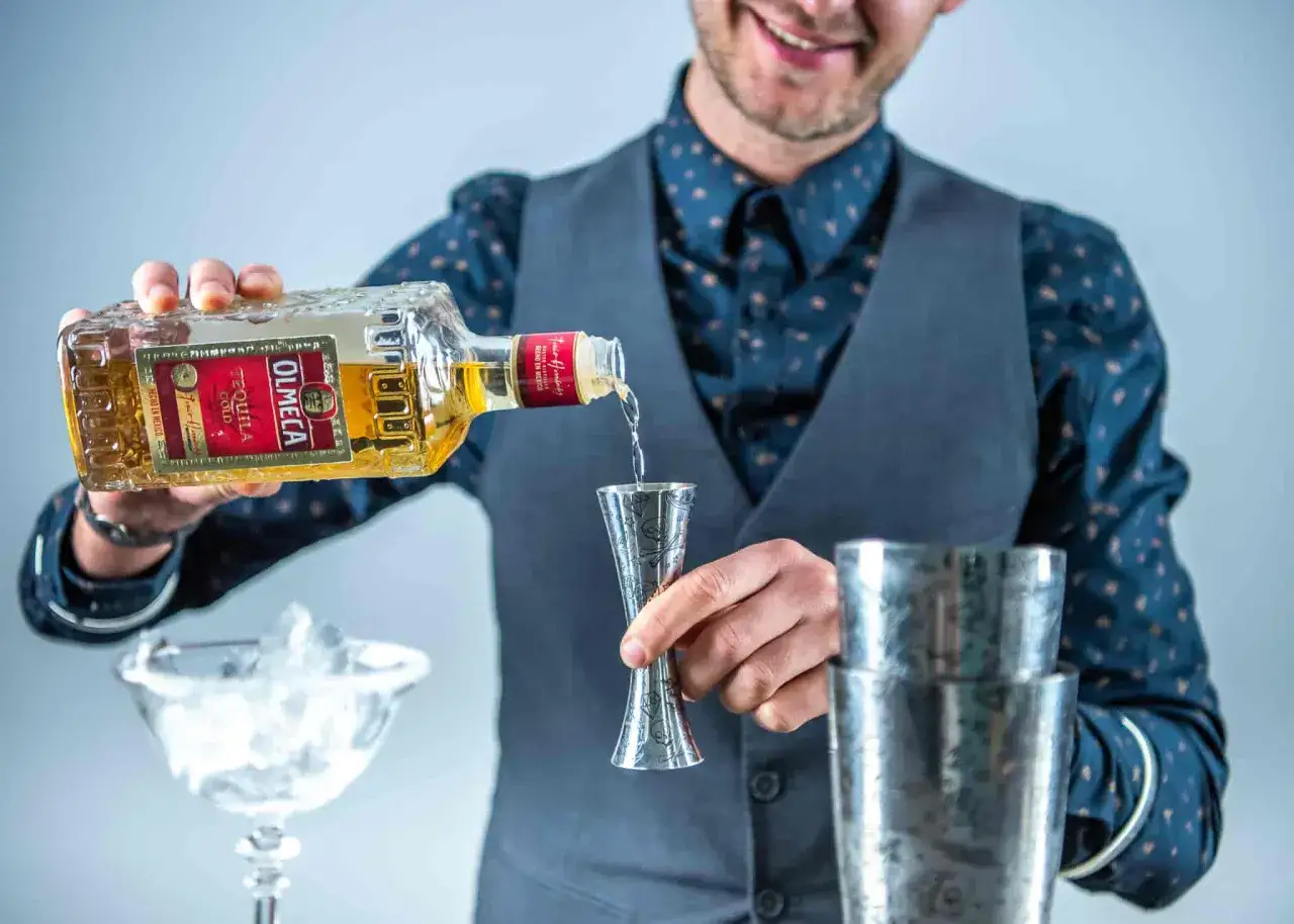 Barman nalewa Olmeca Tequila Gold do jiggera, przygotowując klasyczną margaritę. Różnica między mezcalem a tequilą w tym drinku jest kluczowa.