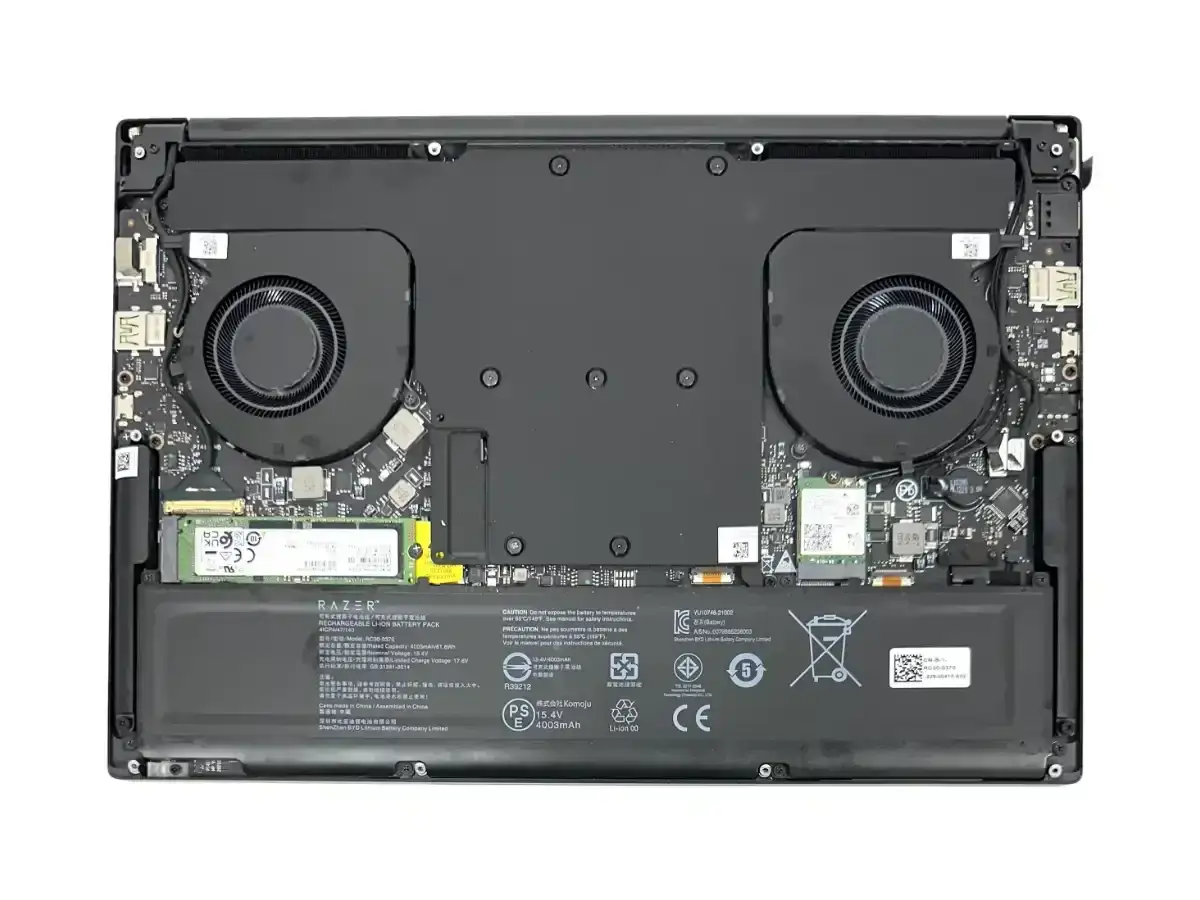 Wnętrze laptopa Razer z widocznymi wentylatorami, dyskiem SSD i baterią. Widać też elementy układu chłodzenia, gdzie kluczowe są termopady.