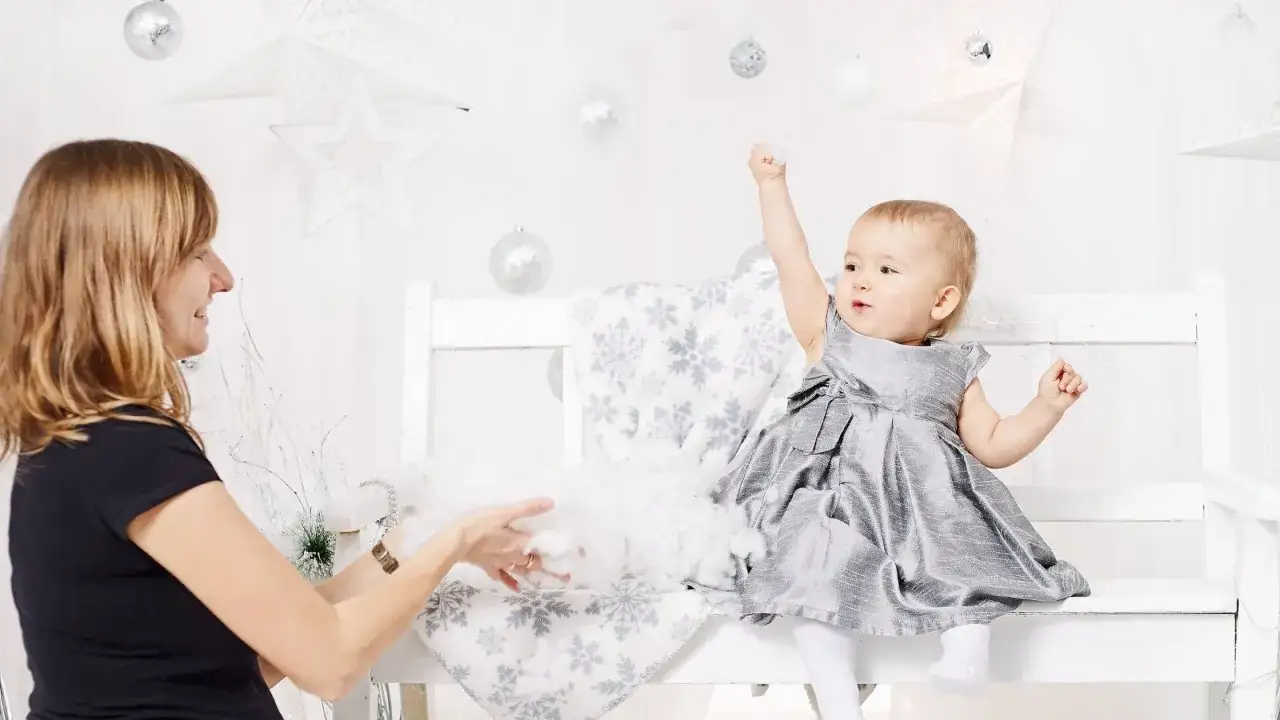 Mama bawi się z dzieckiem, które przeżywa swój skok rozwojowy, radośnie unosząc rączkę.